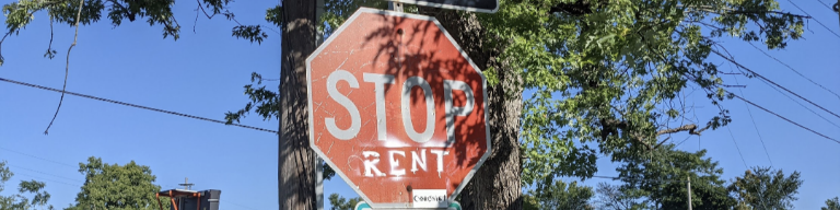 A stop sign with 'rent' written in spray paint underneath 'stop'